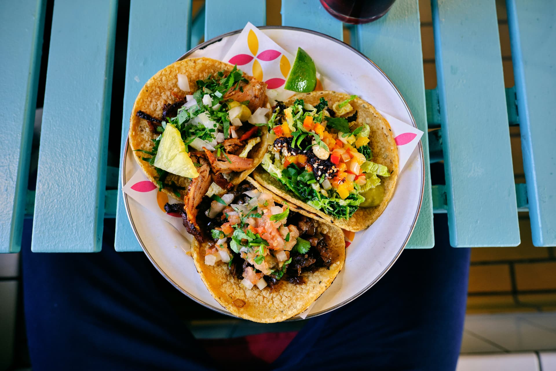 Plate of tacos with lime, cilantro, and salsa on a rustic plate