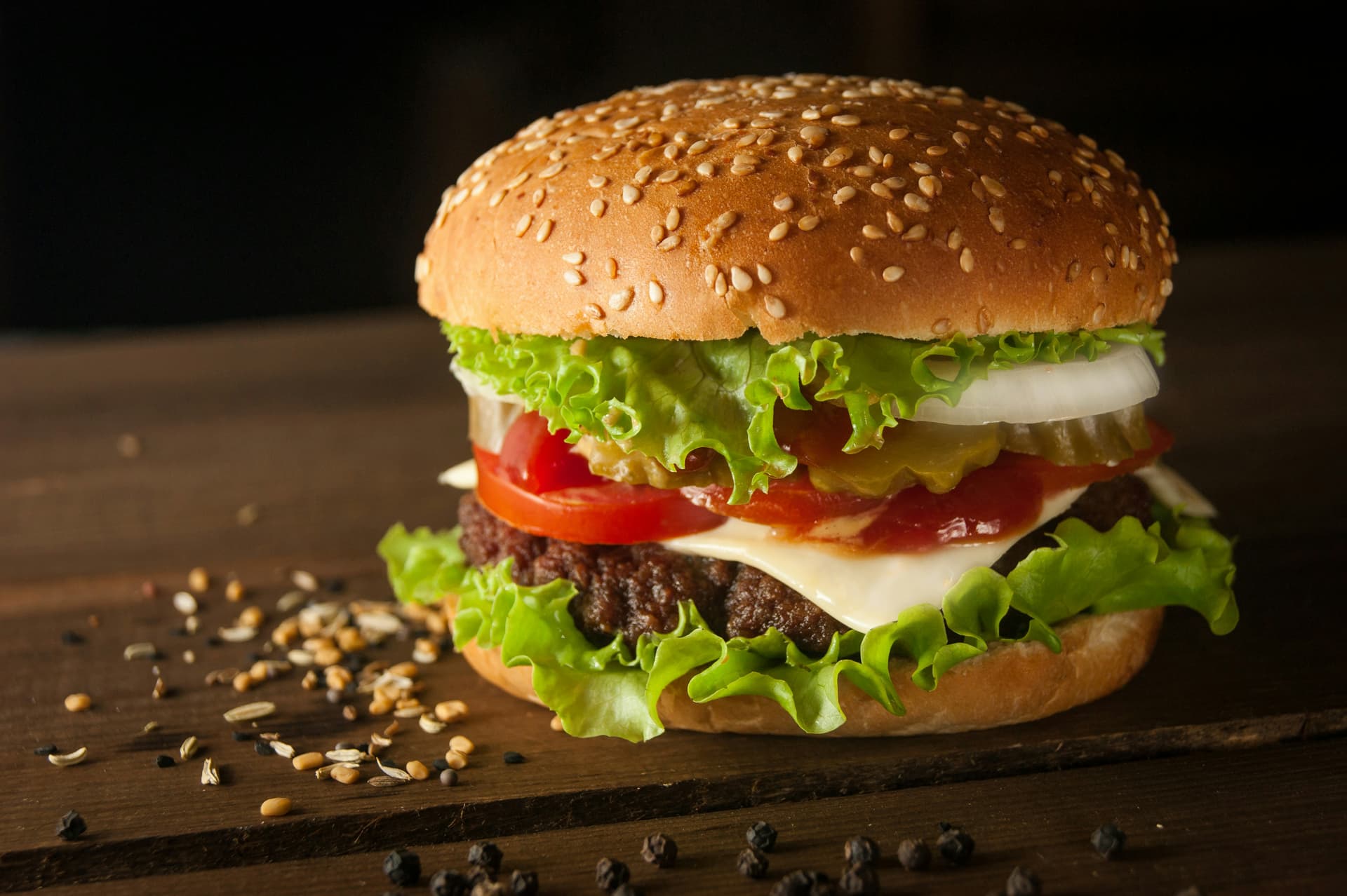 Cheeseburger with lettuce, tomato, and sesame bun on a wooden board